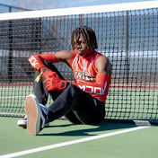 Lifestyle Image of Youth 7v7 Football Athlete Wearing Shock Doctor Red Compression Sleeves on Tennis Court