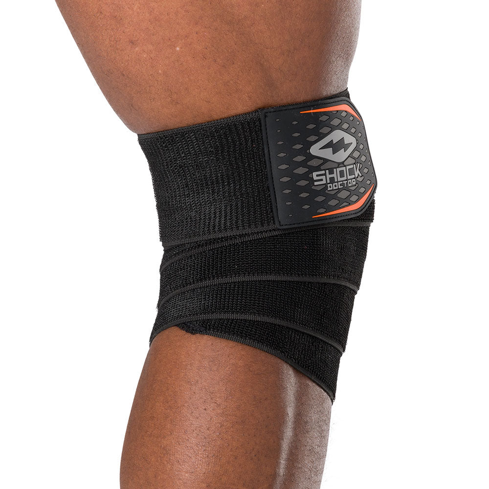 HyperWrap Multi-Use Compression Wrap by Shock Doctor shown in black (back view), providing adjustable support for wrist and knee with wrap-around design.