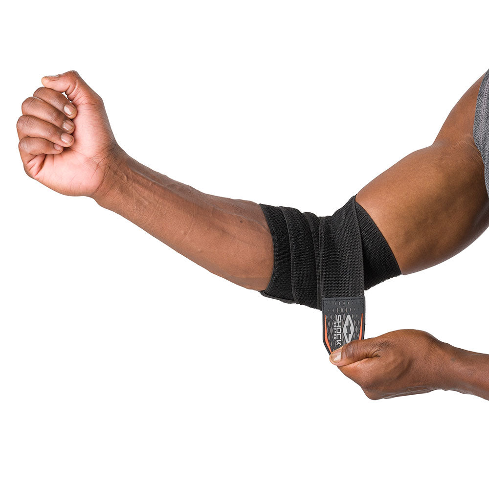 HyperWrap Multi-Use Compression Wrap by Shock Doctor shown in black, providing adjustable support for elbow with wrap-around design. Model wrapping it around their elbow.