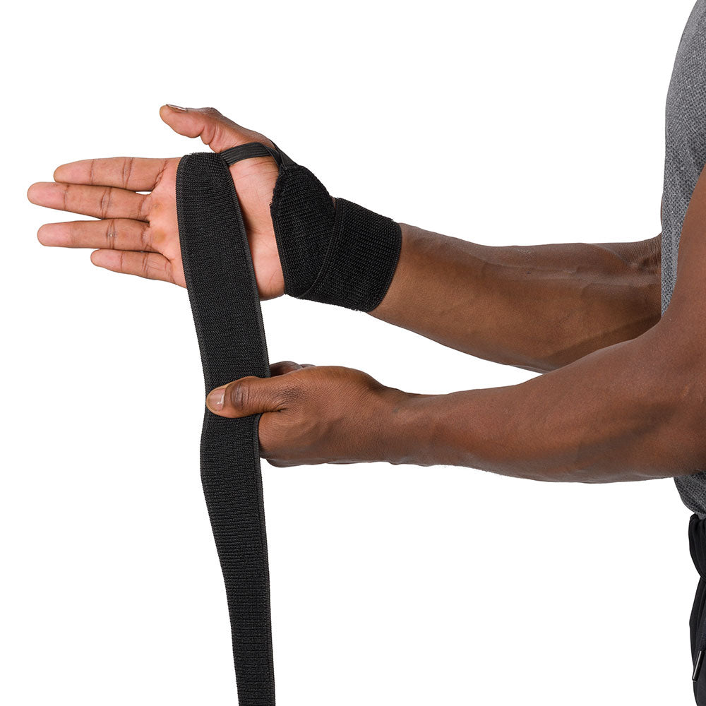 HyperWrap Multi-Use Compression Wrap by Shock Doctor shown in black, providing adjustable support for wrist with wrap-around design. Model wrapping it around their wrist.