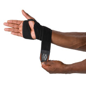 HyperWrap Multi-Use Compression Wrap by Shock Doctor shown in black, providing adjustable support for wrist with wrap-around design. Model wrapping it around their wrist.