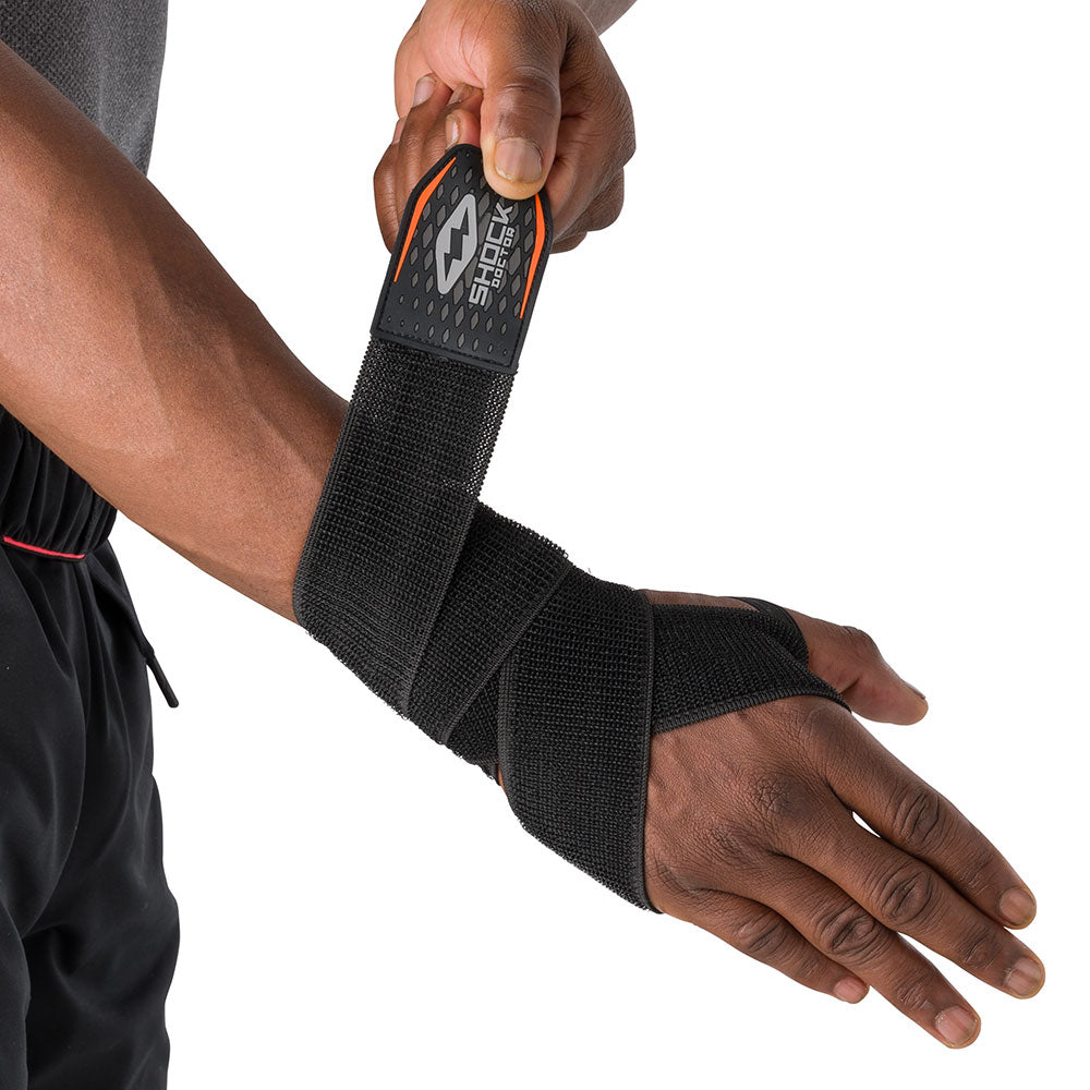 HyperWrap Multi-Use Compression Wrap by Shock Doctor shown in black, providing adjustable support for wrist with wrap-around design. Model wrapping it around their wrist.