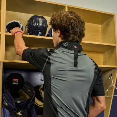 Lifestyle Shot of Male Hockey Player Wearing Protective Shock Doctor Ultra Compression Hockey Short Sleeve Shirt With Integrated Neck Guard while in Locker Room - Back View