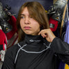 Lifestyle Shot of Youth Female Hockey Player Putting On Protective Shock Doctor Women's Ultra Compression Hockey Long Sleeve Shirt With Integrated Neck Guard Before Game