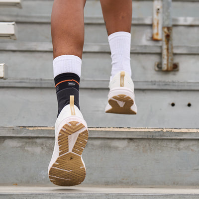 Detail View of Shock Doctor Compression Knit Ankle Sleeve with Gel Support - On Model - Mid Run on Bleachers in Stadium