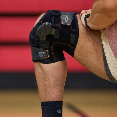 Athlete Stretching While Wearing Shock Doctor Knee Brace with Dual Wrap & Heavy-Duty Hinges (Detail View of Hinge)