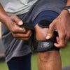 Athlete Strapping On Shock Doctor Dual Strap Knee Wrap While Lifting Weights