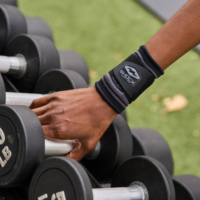 Athlete Wearing Shock Doctor Compression Knit Wrist Sleeve with Strap While Lifting Dumbbells